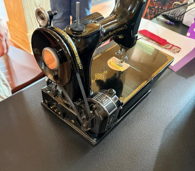 A treadle sewing machine set up and threaded on the work table.