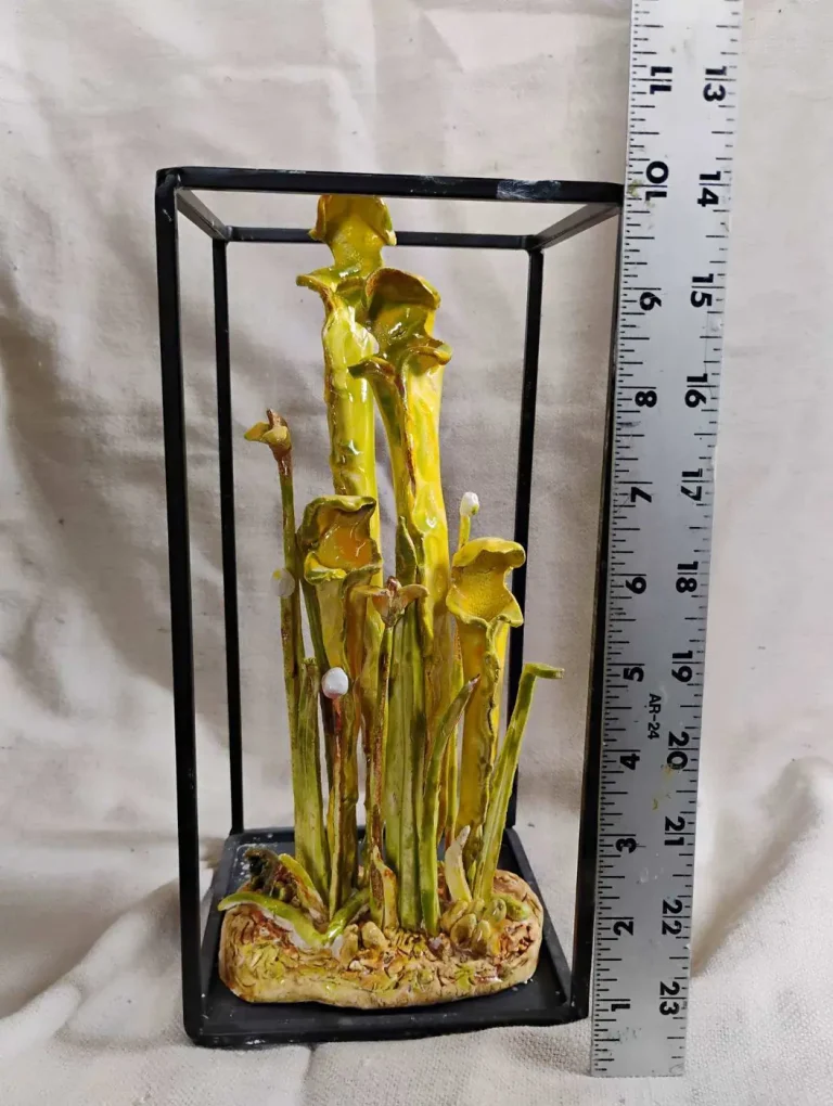 A sculptural yellow pitcher-plant piece displayed beside a ruler for scale