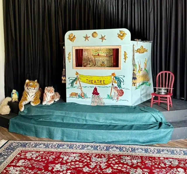 A miniature puppet theater with animal puppets on its stage