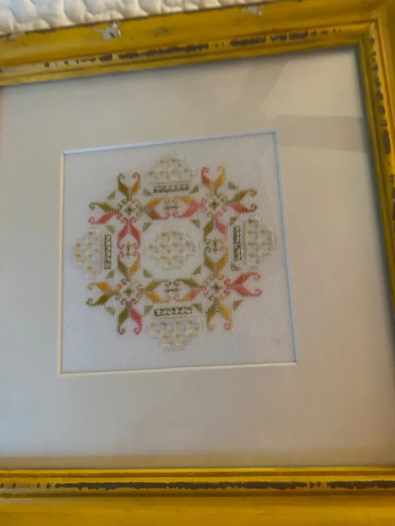 A framed needlework sampler in a gold frame