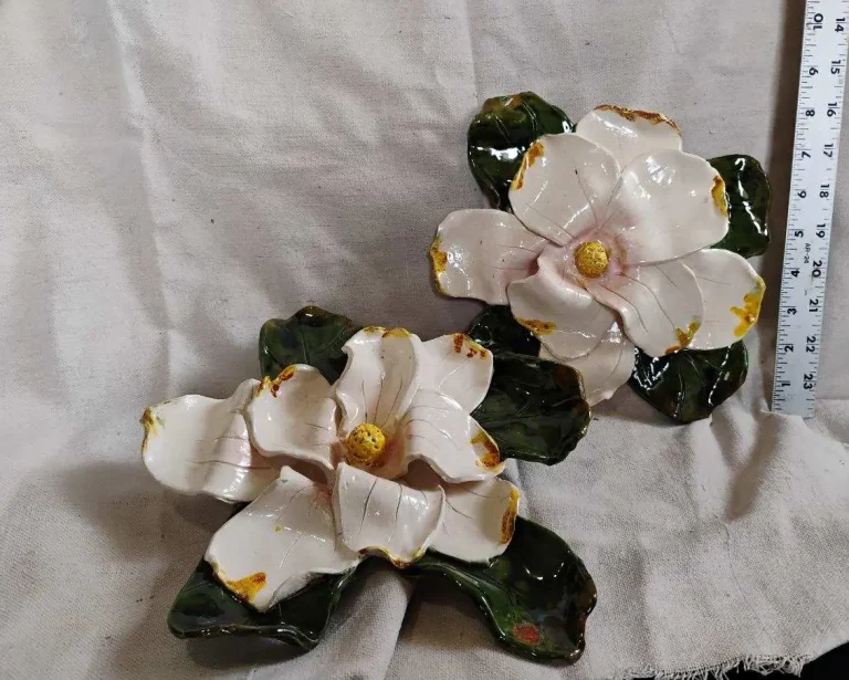 Ceramic magnolia blossoms with leaves laid beside a ruler