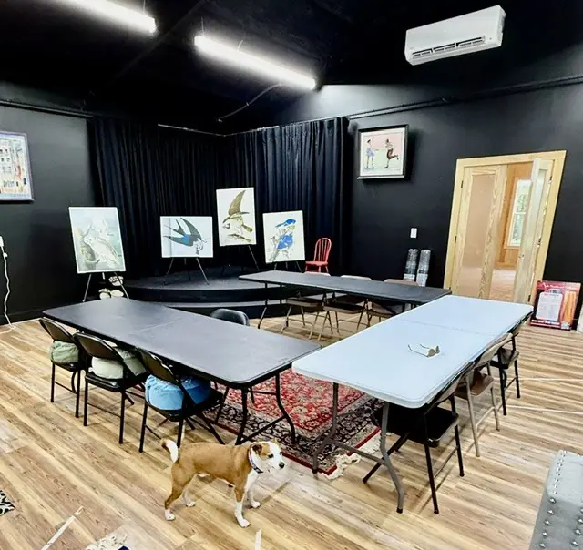 The black box theater set up with tables, a dog resting nearby