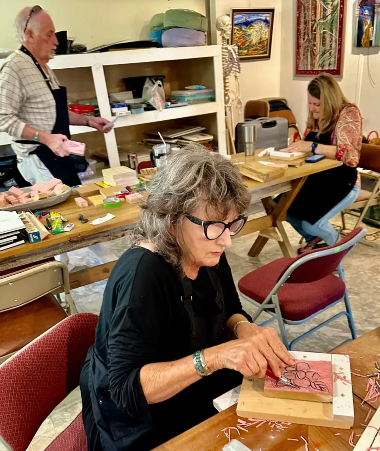 A woman works on a mosaic piece at the needlework table