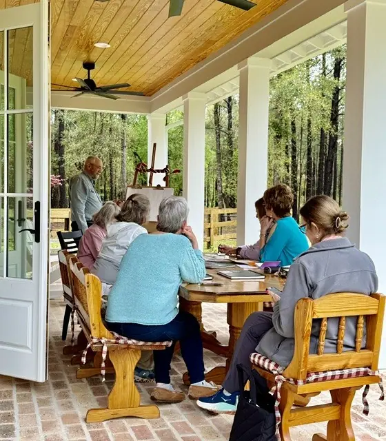 Painting students sit at tables on the covered porch