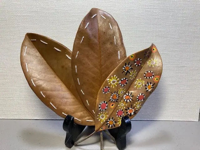 A ceramic magnolia leaf dish with a painted floral pattern, on a stand