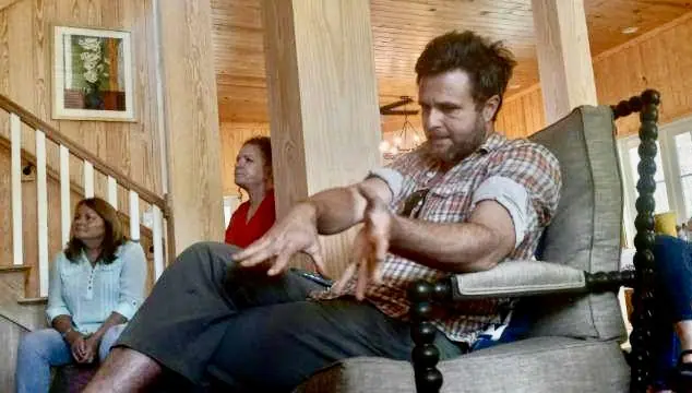 Three adults relaxing together on a porch bench