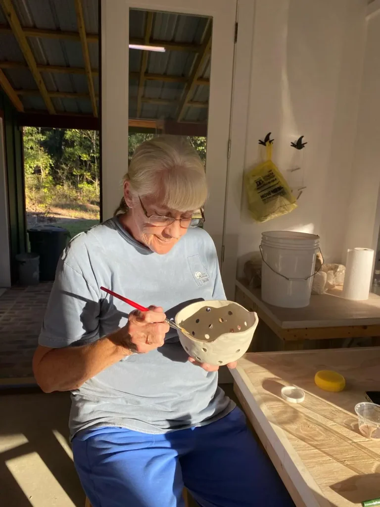 A woman glazing a bowl by hand with a paintbrush