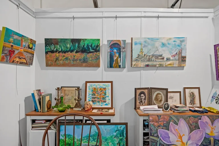 Framed paintings and fiber art pieces displayed on a gallery wall