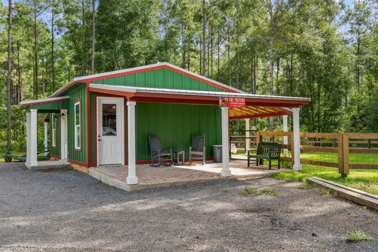 A green building with a red roof and a covered porch