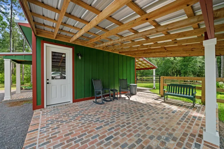 A covered breezeway with a wood plank ceiling and a bench