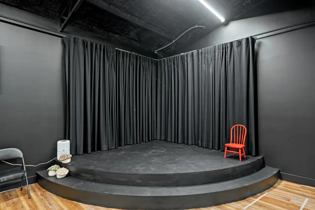 The Black Box stage with a single red chair under the lights.